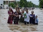 A family wades through a waterlogged road after heavy rainfall in Ahmedabad, Gujarat, on Wednesday. Intense monsoon rains and flooding have hit Gujarat, killing at least 28 people in the last three days, according to government officials.(AP)