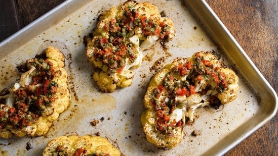 This image released by Milk Street shows a recipe for cauliflower steaks with pickled peppers, capers and parmesan. (Milk Street via AP)